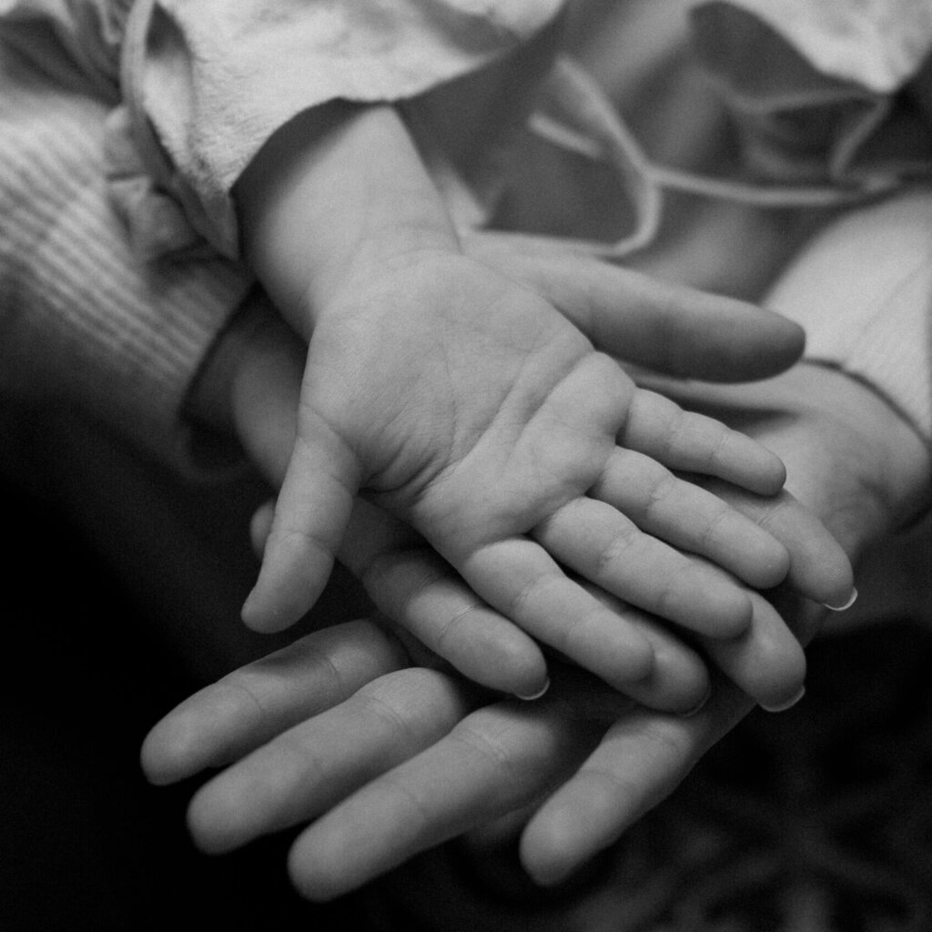 Black and white image showing childrens hands in parents hands.